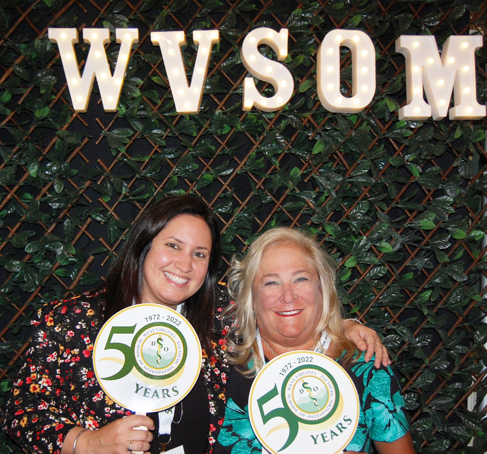 SWC Managing Director, Alicia Luckton with another attendee posed under WVSOM light sign