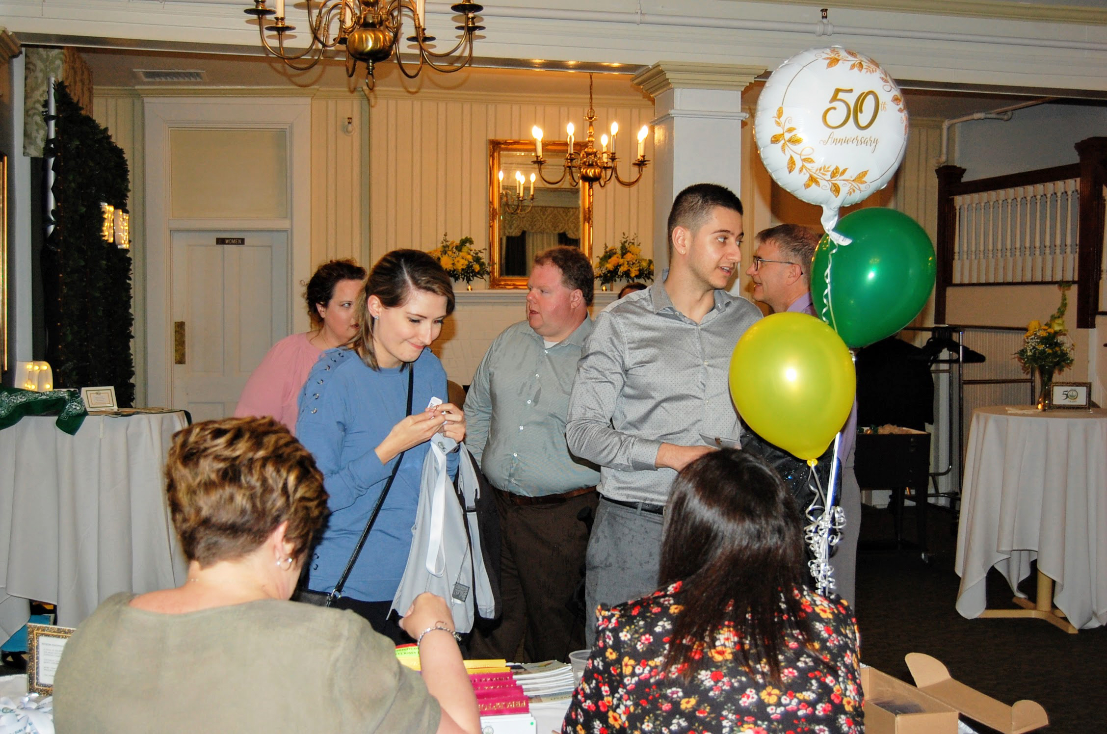 Attendees arriving at registration desk, 50th anniversary balloons visible