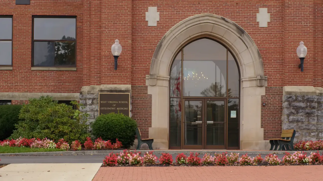 brick building with archway entrance, brick walk way with flower landscaping