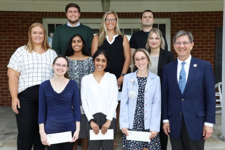 Nine students stand in front of the Roland P. Sharp Alumni Conference Center with WVSOM president James W. Nemitz, Ph.D.