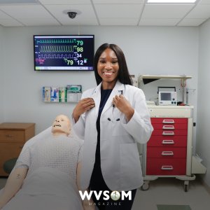 A WVSOM student stands next to a human-patient simulator