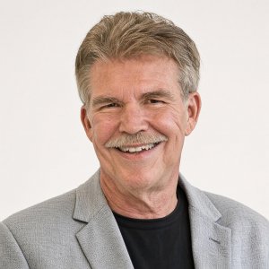 A man wearing a gray dress jacket, smiling