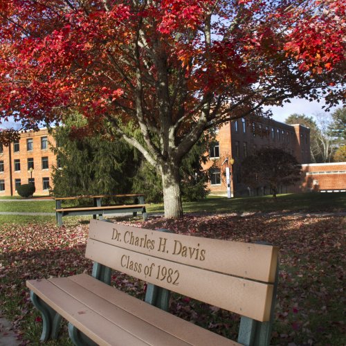 Dr. Charles H. Davis Class of 1982 engraved bench under red leafed tree