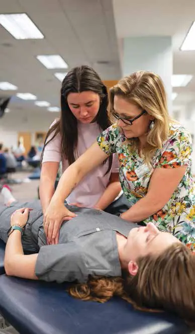 student and instructor work on student-patient laying on table